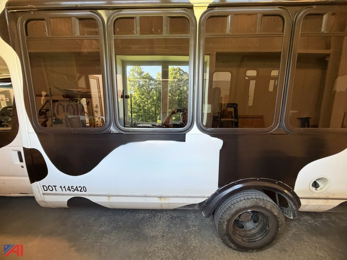 Ford E450 Transit Bus side view showing wheelchair lift area, black and white painted exterior, passenger windows along the side, DOT number 1145420 near the front wheel.