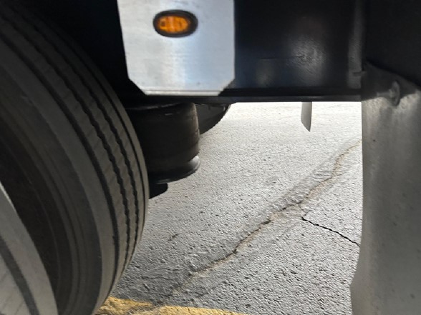 Trailer deck and wheel area with label reading orange circle reflectors and structural frame; close-up of rear wheel well and suspension components