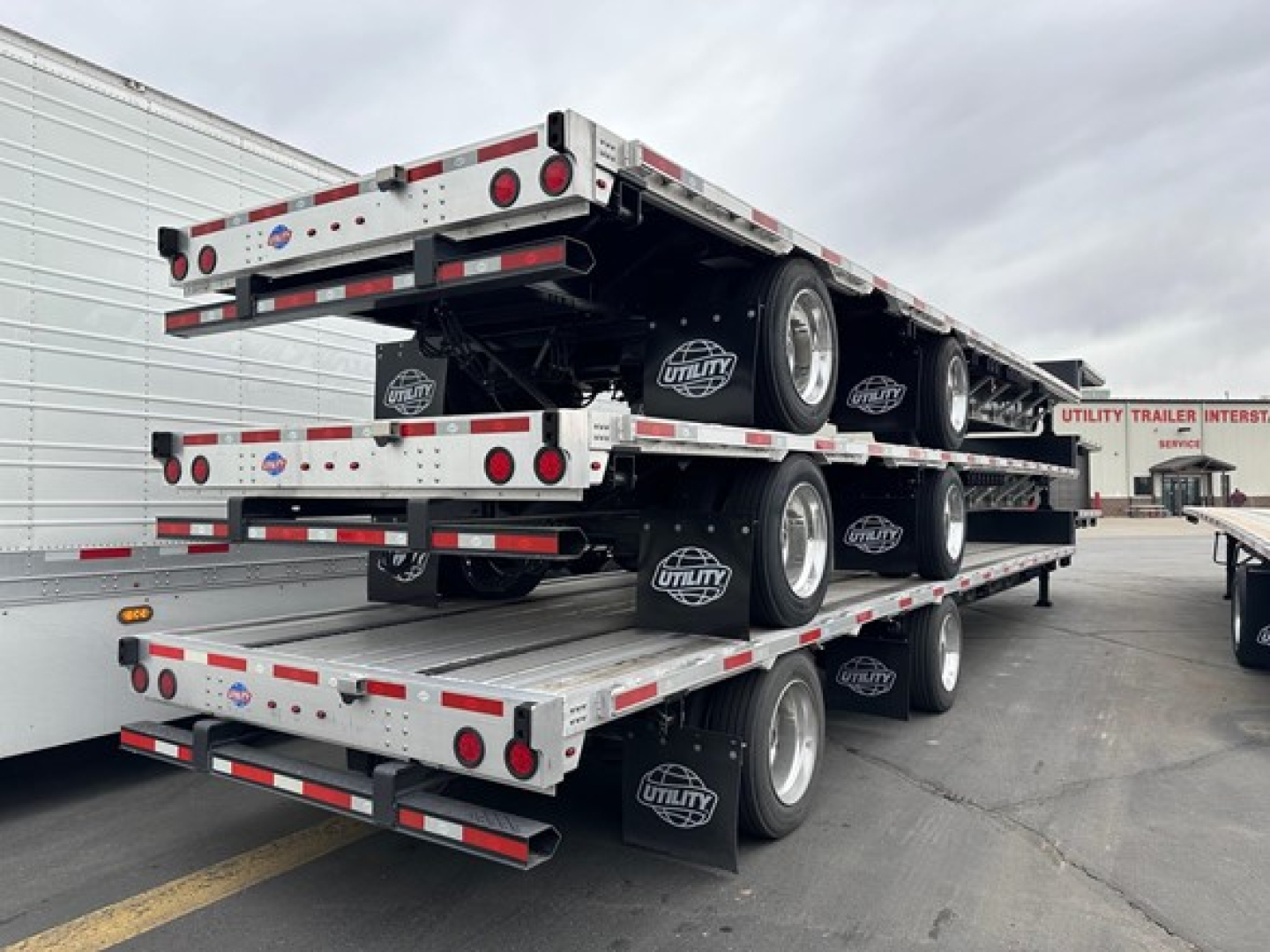 Trailer stack showing multi-level Utility drop deck trailers with spare tires and rear lighting.
