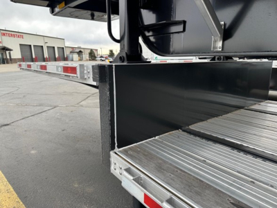Drop deck trailer side view showing metal ramp and platform with reflective striping and welded steel frame