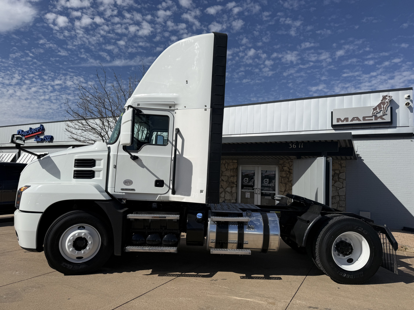 Conventional Daycab truck side view showing Mack AN42T cab and fuel tanks with chrome steps.