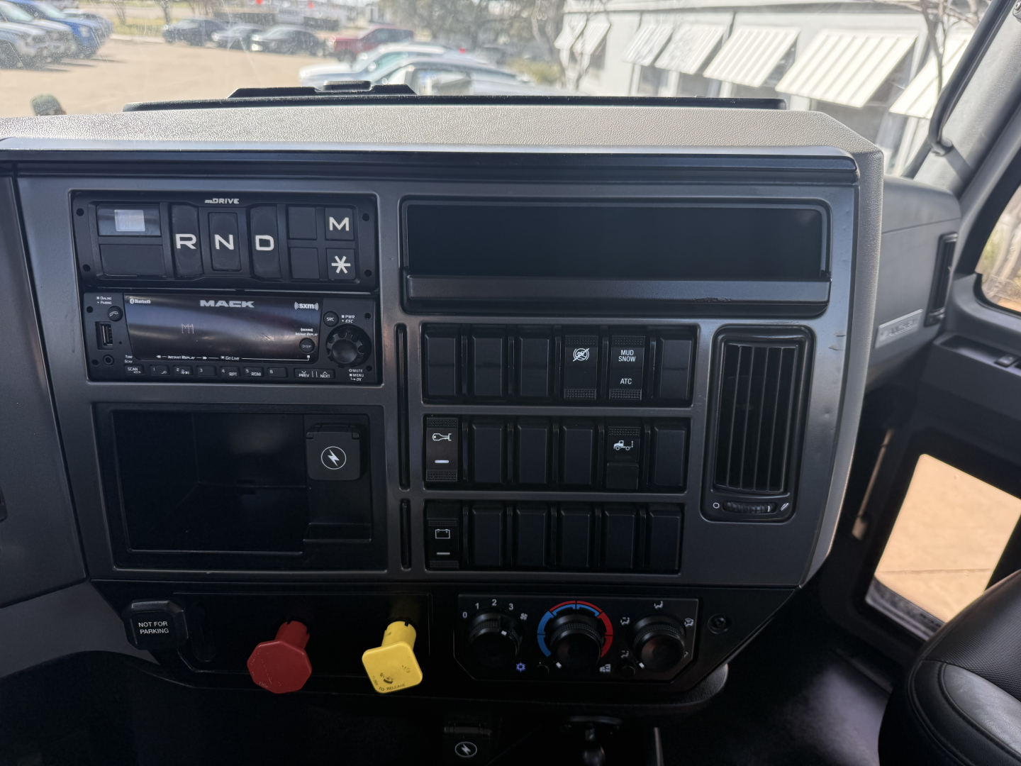 Mack AN42T truck dashboard with gear indicator, radio, and control panels visible; various switches and knobs, dual air vent, windshield view.