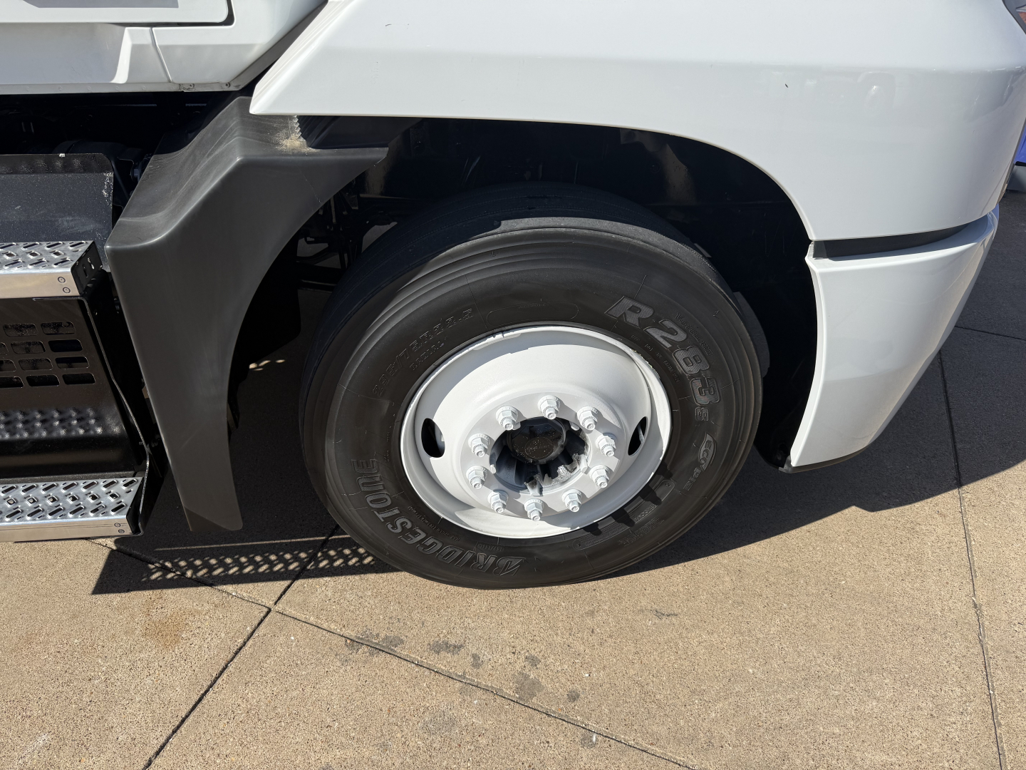 Truck wheel and fender close-up showing front tire with rim on a Mack AN42T conventional daycab.