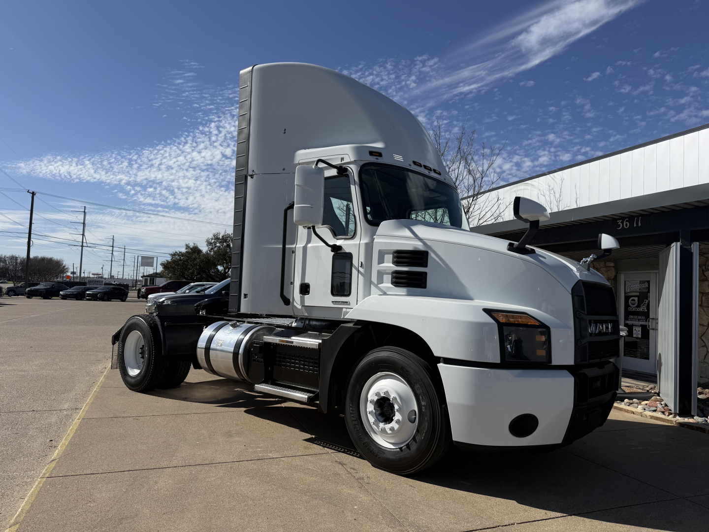 Truck cab showing Mack AN42T Daycab, front-left view, with sleeper behind cab, white exterior, fuel tanks and side skirts visible.