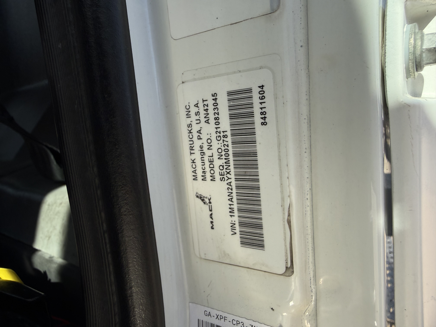 Mack AN42T truck door jamb label showing VIN and stock info; barcode and model details readable.