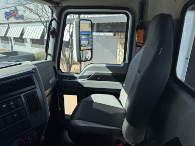 Truck cab interior showing driver seat and dashboard of 2022 Mack AN42T with large side mirror and window glare.