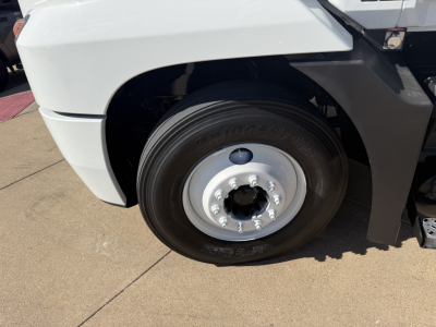 Front wheel and fender of a 2022 Mack AN42T conventional daycab showing front tire, rim, and part of bumper.