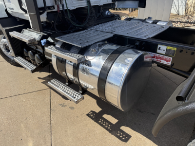Fuel tank and side steps on a Mack AN42T truck showing chrome cylindrical fuel tank and textured metal steps with surrounding chassis components.