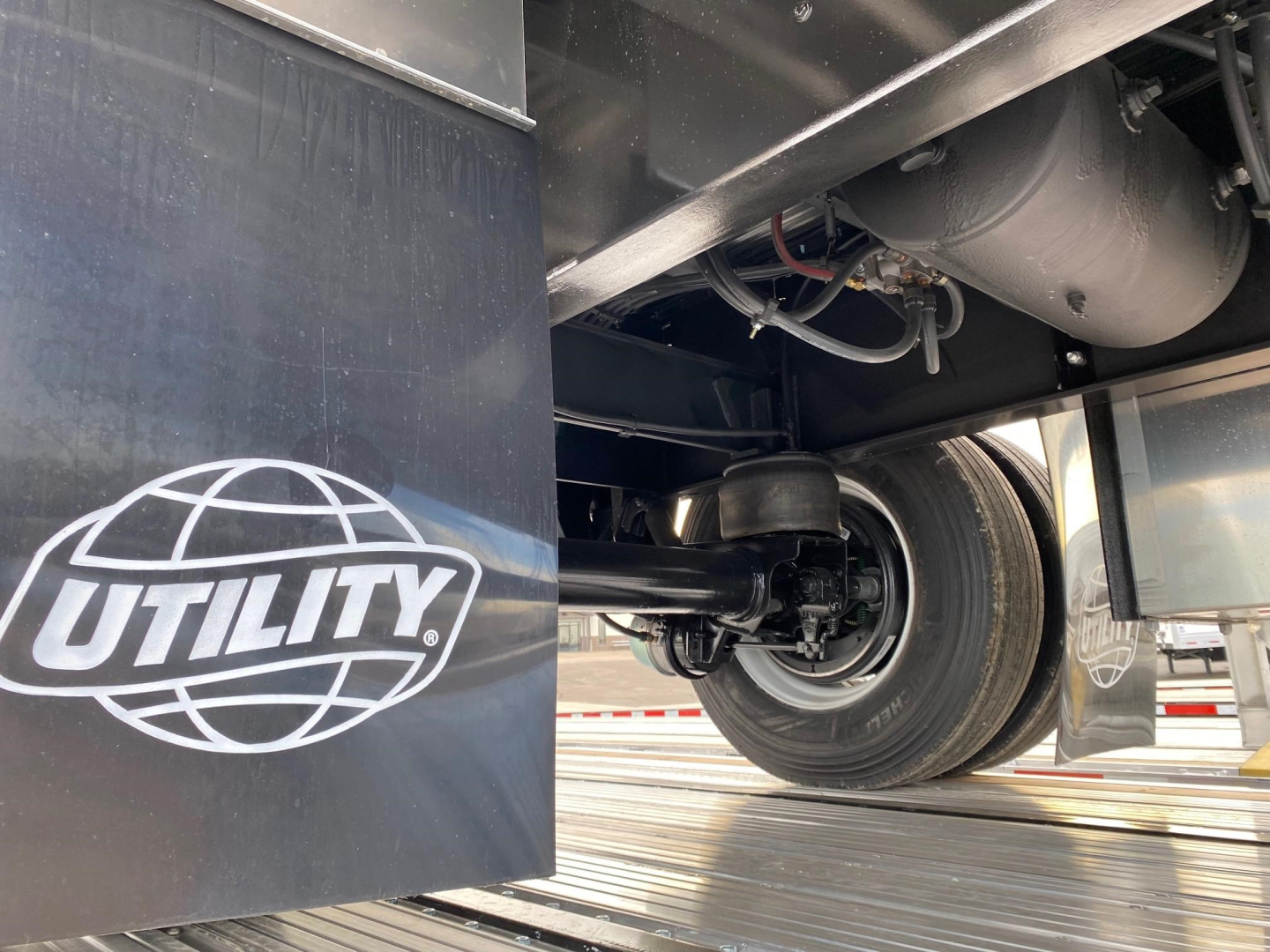 Utility 4000Ae trailer undercarriage showing wheel, suspension, and hydraulic lines with Utility logo panel.