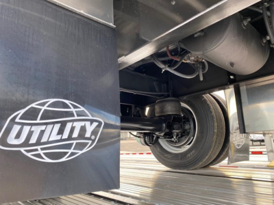 Flatbed trailer undercarriage with wheel and suspension visible, Utility logo on mudguard. Text not fully legible but shows trailer underside components.