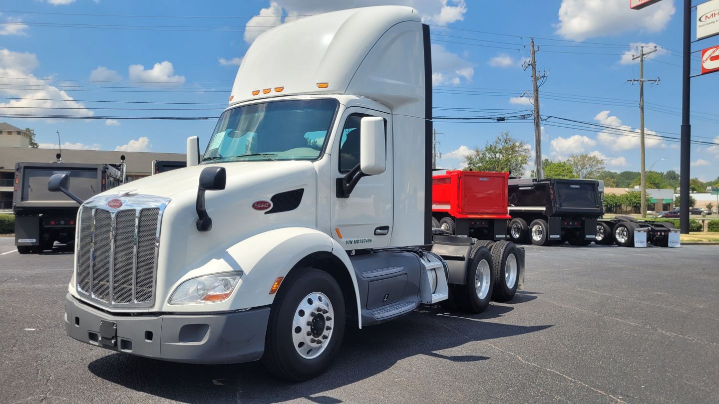 Peterbilt 579 daycab tractor truck in white, side view showing cab, grille, dual rear axles, and sleeper height.