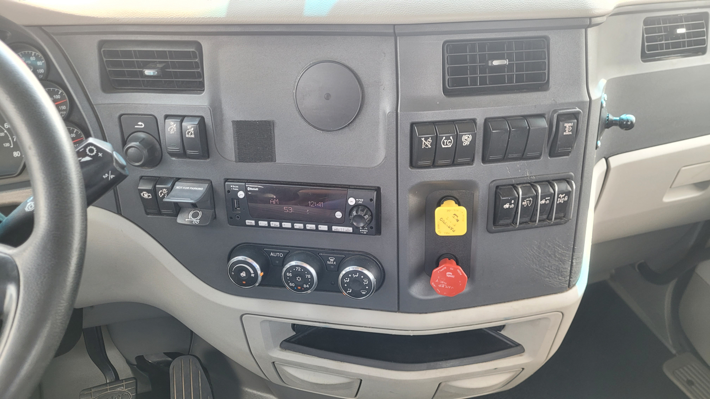 Peterbilt 579 interior dashboard showing control panel with knobs, vents, and yellow and red warning/cap accessories.