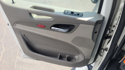 Peterbilt 579 truck interior door panel showing window controls and door pocket, beige plastic with Peterbilt emblem.