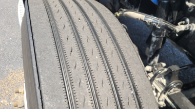 Front left tire of a 2021 Peterbilt 579 conventional daycab showing tread pattern and wheel area.