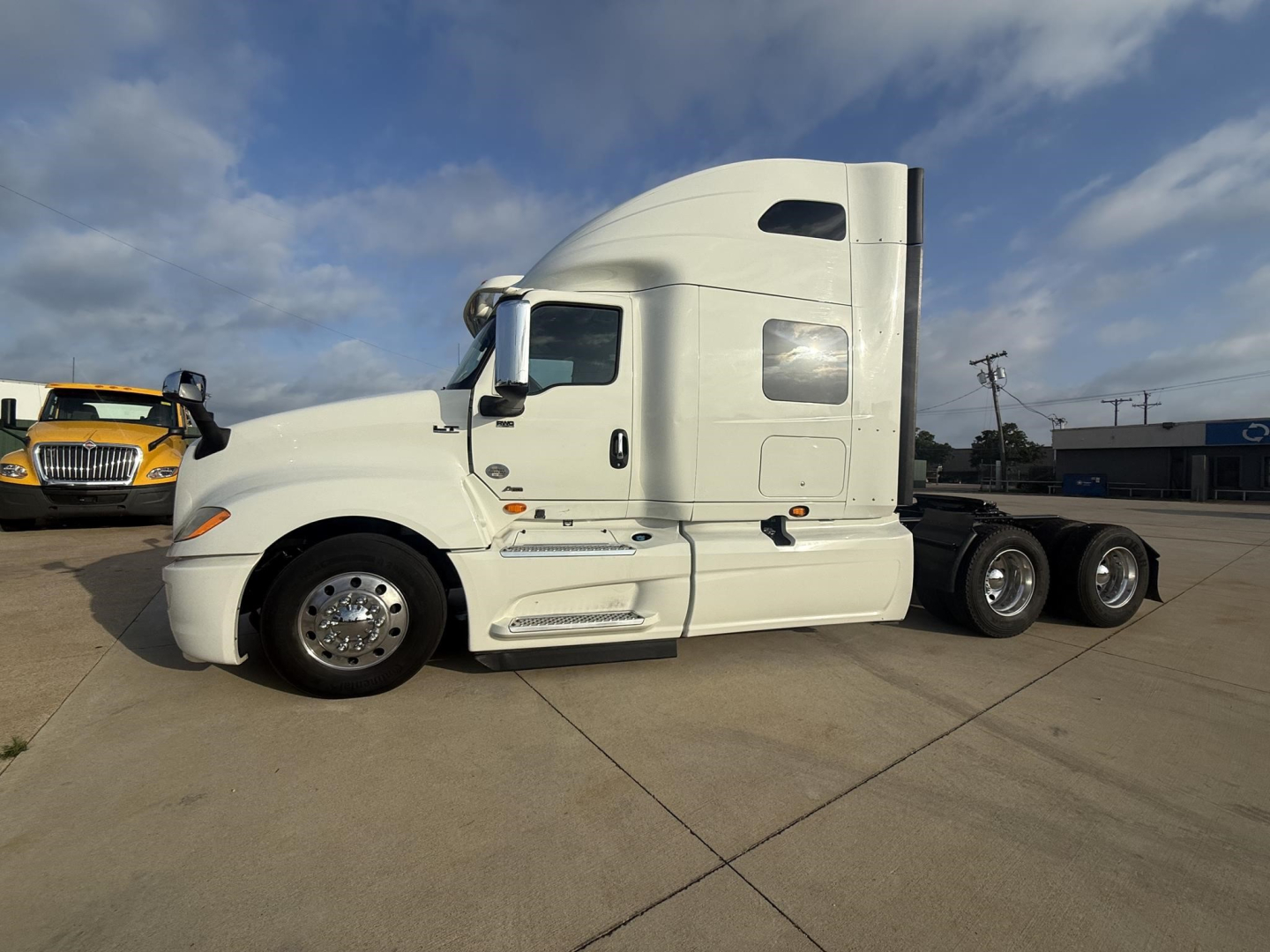 International LT truck side view showing sleeper cab and tandem rear axles, white exterior, no visible text on body.