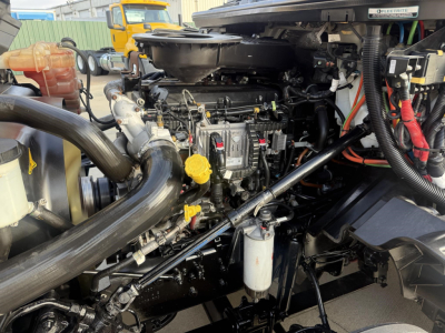 Truck engine bay of a 2020 International LT showing engine components, hoses, yellow dipstick, and filter canister.
