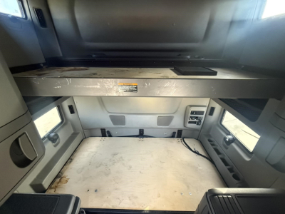 Interior cab area of a 2020 International LT showing sleeper bunk area with storage shelf, control panel, and empty floor space.