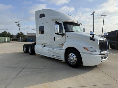 International LT truck in white cab and sleeper, side view showing front grille, headlights, and wheel with 6 tires visible.