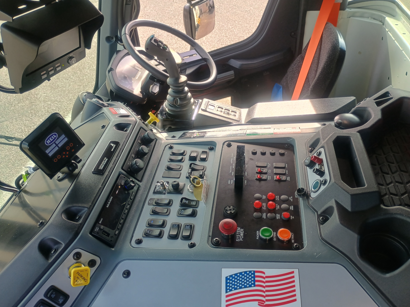 Cab interior of a 2026 Mack LR64 chassis showing steering wheel, control panel with numerous switches, display screen, and seating area.