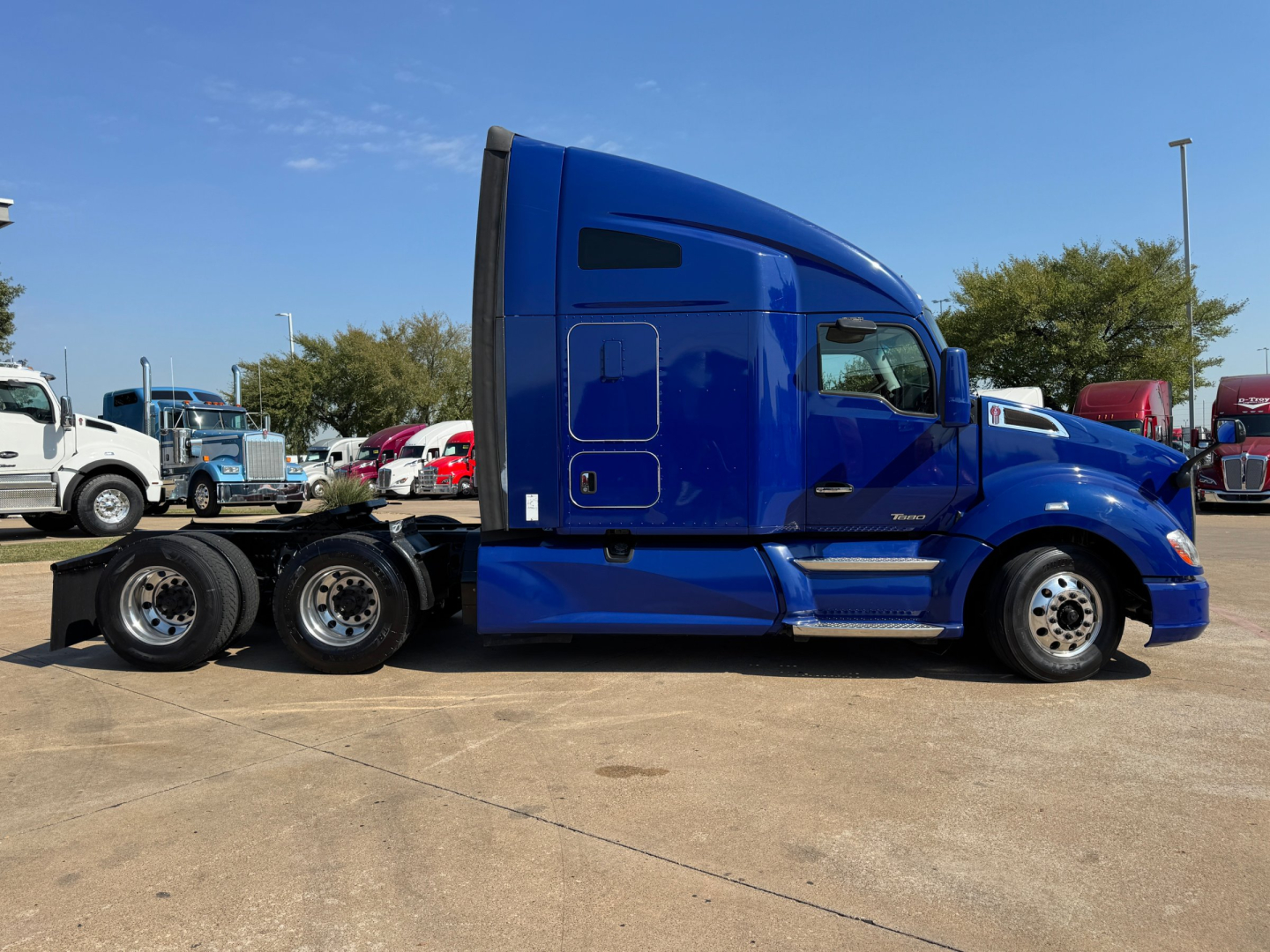 Kenworth T680 blue sleeper cab tractor viewed from side showing tractor and chassis with multiple rear axles.