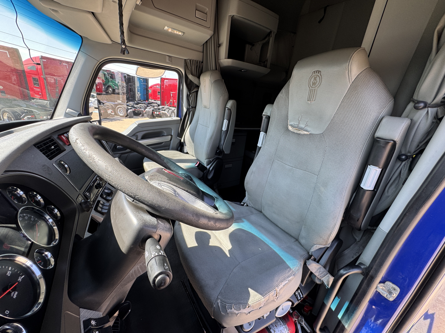 Vehicle cab interior of a 2019 Kenworth T680 with steering wheel, driver seat, and dashboard visible.