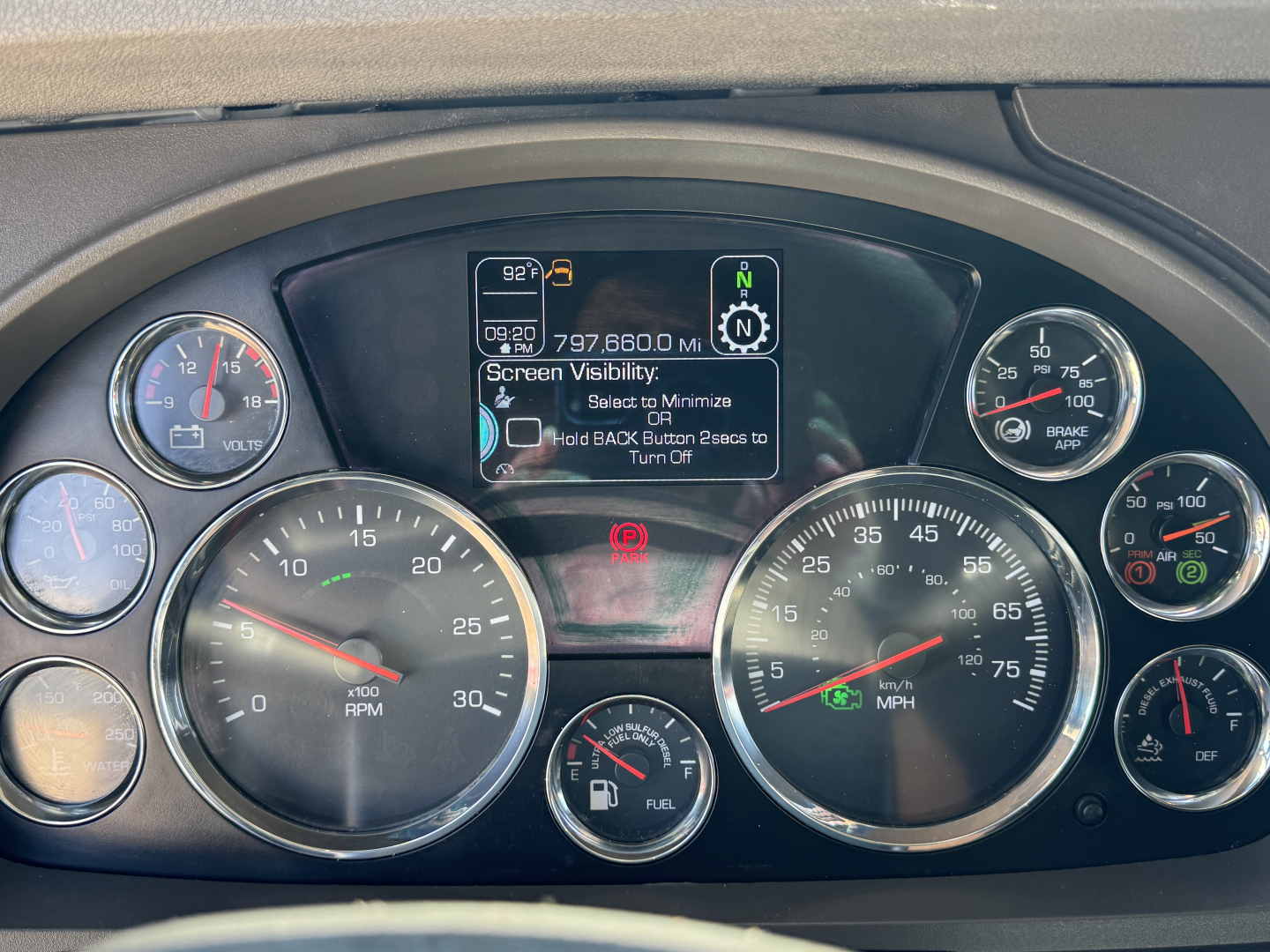 Dashboard of a Kenworth truck showing multiple gauges including rpm, speedometer, fuel gauge, and a central digital display with vehicle status icons.