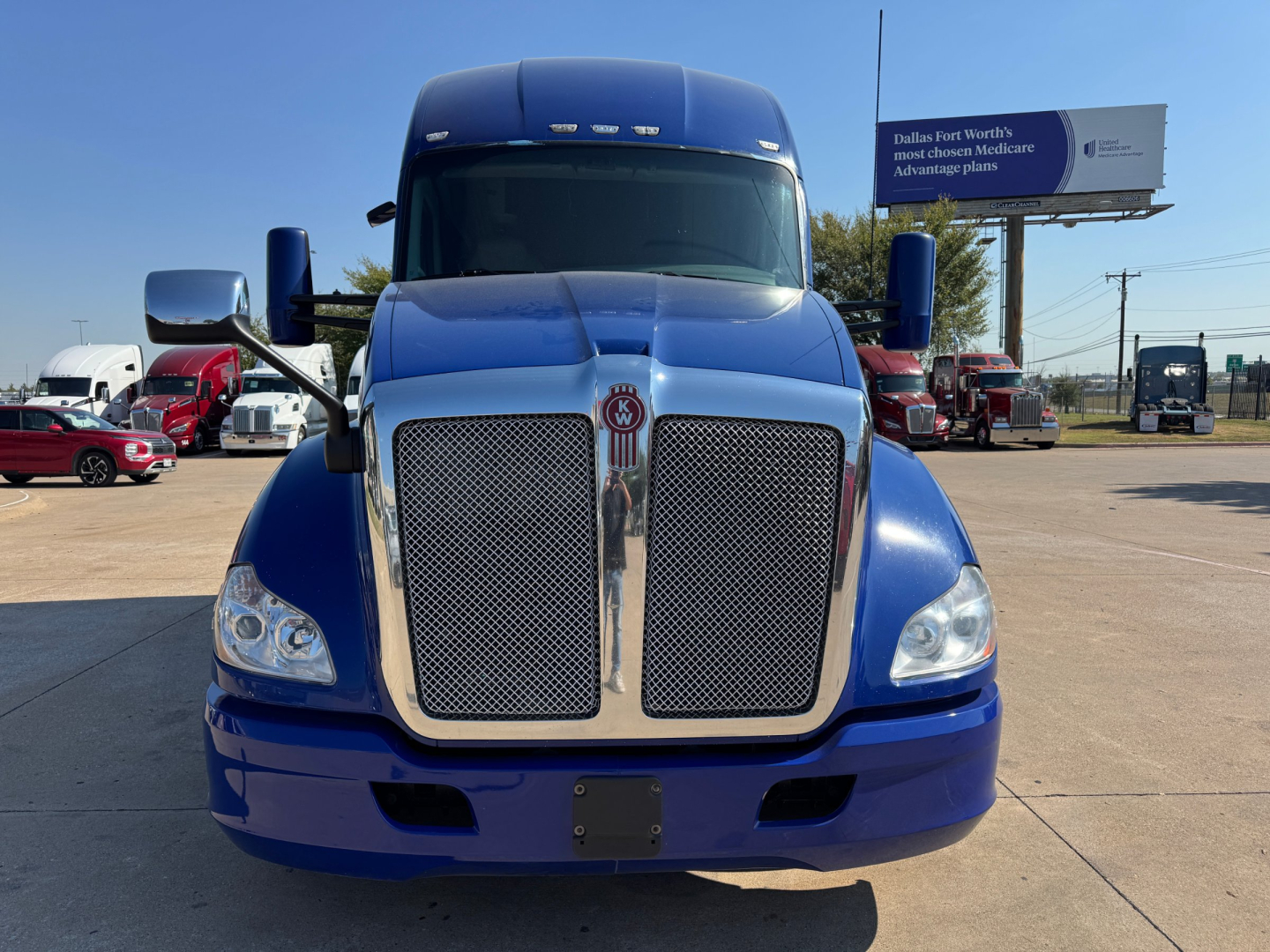 Kenworth T680 front view showing chrome grille with mesh inserts, blue paint, large bumper, and dual headlights.
