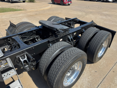 Kenworth T680 tractor truck chassis showing dual rear axles and tires with metal frame and suspension components visible.