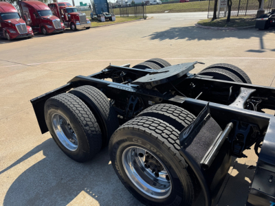 Kenworth T680 chassis showing rear wheel assemblies and frame with dual rear axles. Visible details include: no cab, exposed fifth wheel area, tires, chrome rims, and suspension components.