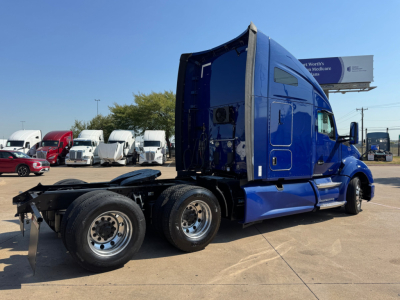 Kenworth T680 tractor truck side/back view showing blue exterior and dual rear axles with cab sleeper, no visible text or labels readable.