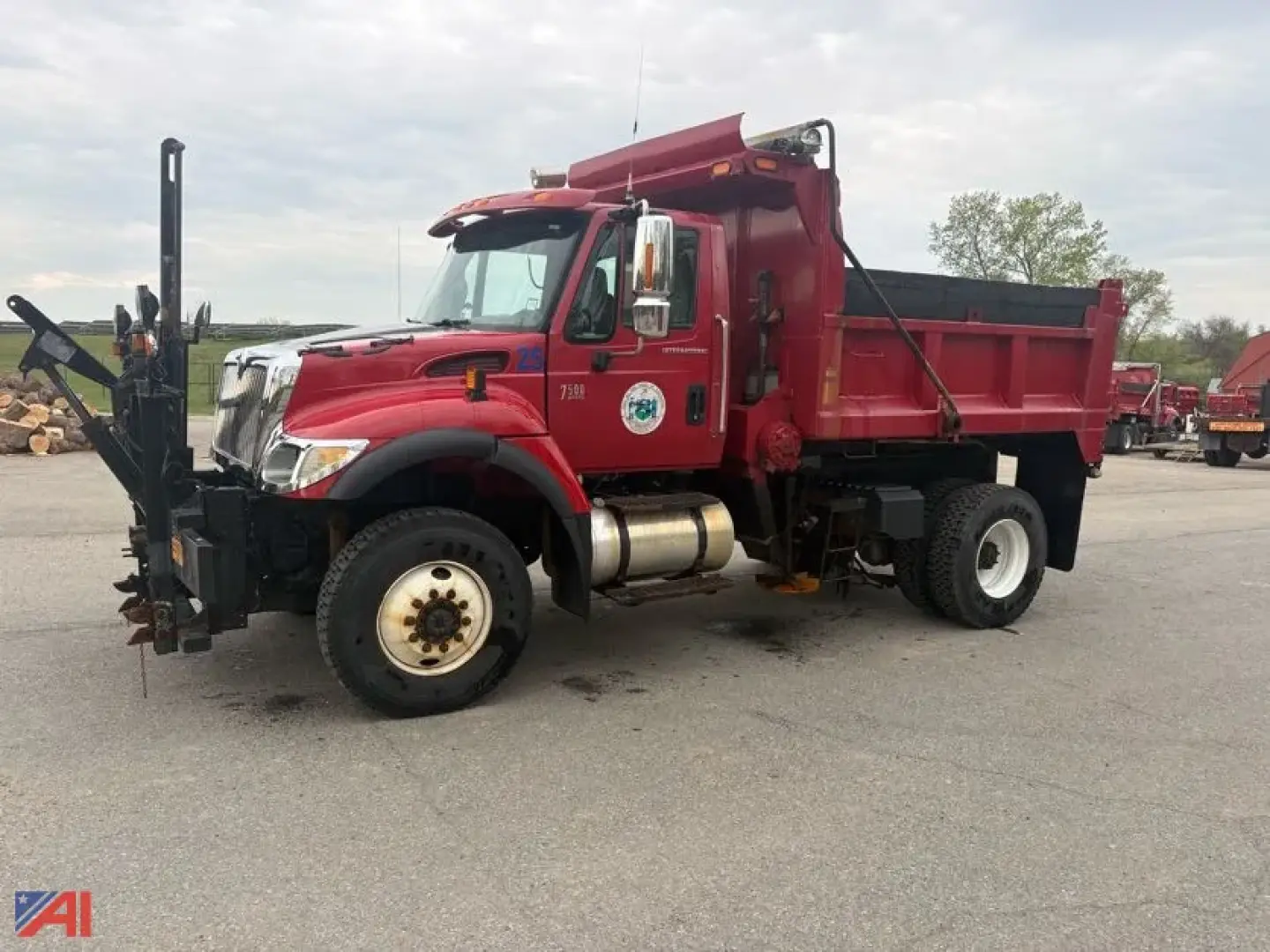 Side view of a red 2007 International WorkStar 7500 dump truck with plow, wing, and sander. Truck has black plow mounting, white wheels, and a dump bed.