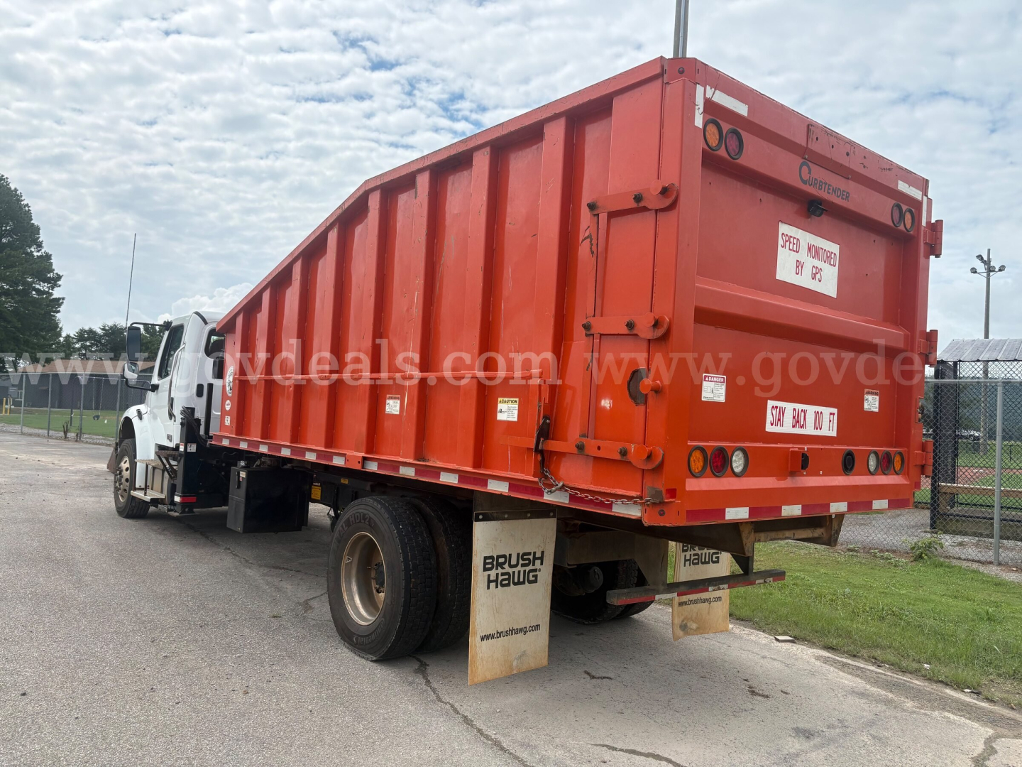 Truck rear view showing orange dump bed on Freightliner M2 106 with mud flaps and rear lights