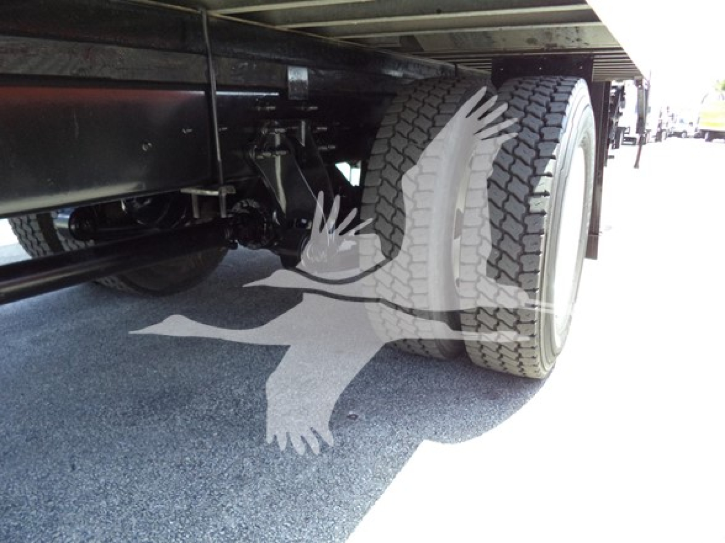 Truck rear undercarriage with dual rear tires and suspension visible.