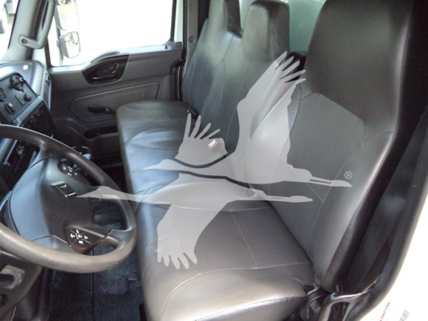 Interior cab view of a 2021 International MV showing driver seat and bench passenger seat with steering wheel and dashboard visible.