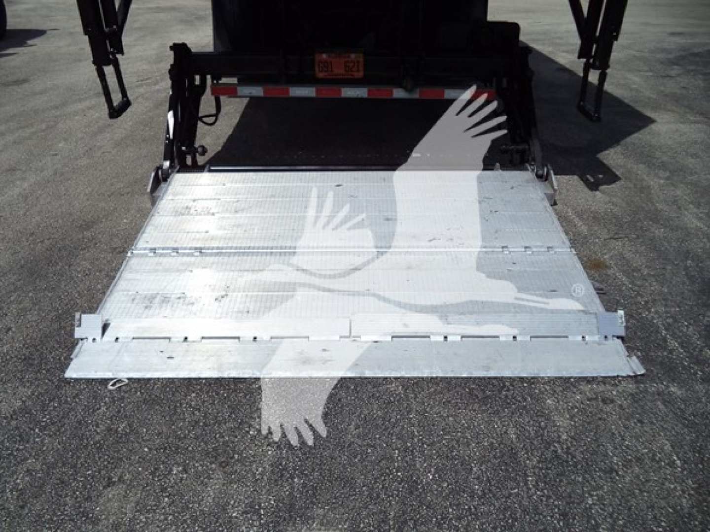 Truck rear with aluminum fold-down ramp extended, rear view showing loading platform and hitch area; MV series box truck tailgate ramp in metal with hinge details.