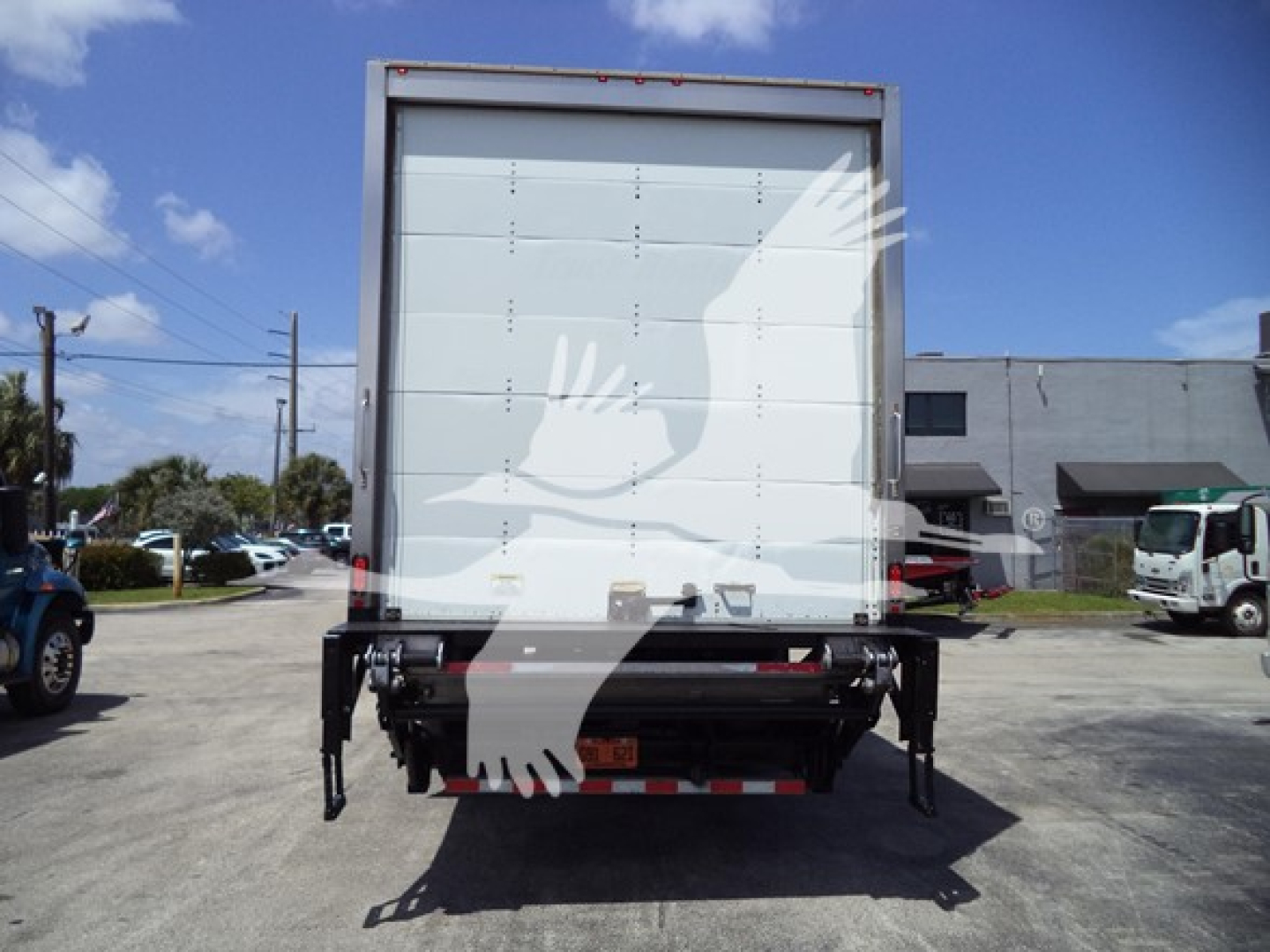 Rear view of a box truck with a white cargo area and black undercarriage; no visible logos; blue sky; parking lot.