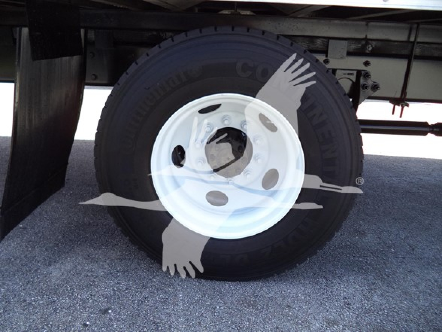 Wheel and tire assembly under a box truck shows a white steel wheel with a black tire; faint branding on tire