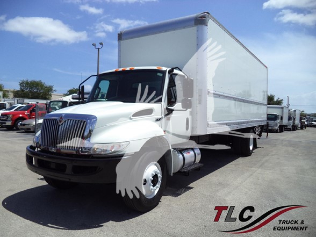 Box truck with white cab and cargo box, 2021 International MV, side view showing front grille, headlights, and cargo box, dealership lot in background.