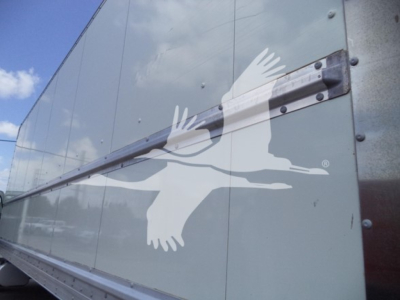 Box truck side showing a white bird decal on light gray exterior and a metal hinge/strap along the edge of the trailer door.