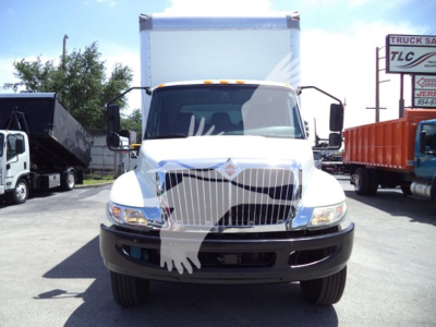 Truck front view showing International MV box truck with white cab, large grille, and black bumper. License-free area, dual headlights, cab mirrors, box truck rear cargo area visible.