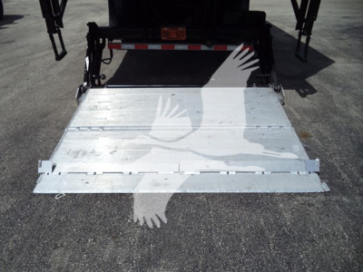 Truck rear with aluminum fold-down ramp extended, rear view showing loading platform and hitch area; MV series box truck tailgate ramp in metal with hinge details.