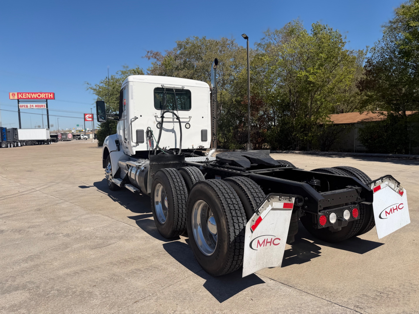 Kenworth T880 daycab rear/side view showing dual rear axles and trailer-to-go chassis with white mud flaps and MHC logo.
