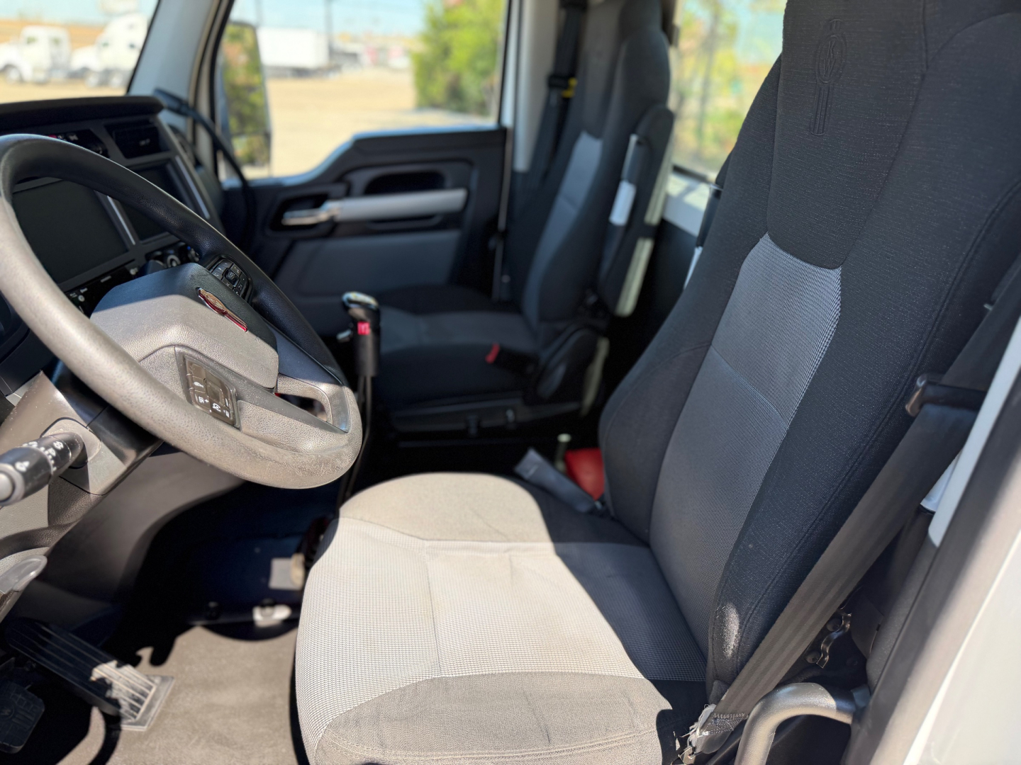 Kenworth T880 interior with steering wheel and dual front seats, gray fabric upholstery visible.