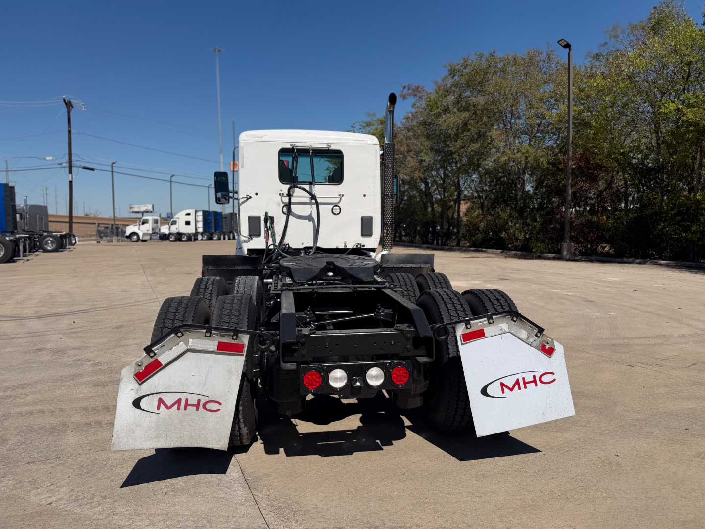 Kenworth T880 tractor rear view showing mud flaps with MHC logos and fifth wheel area.