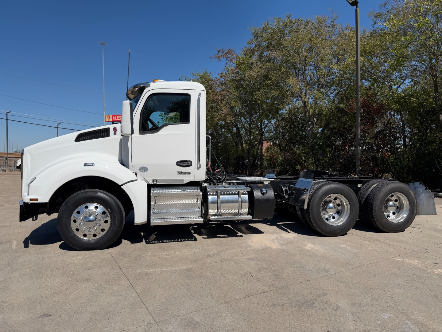Kenworth T880 conventional daycab truck side view showing chrome fuel tanks and dual rear axles.