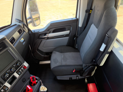 Truck cab interior showing driver's seat and dashboard of a Kenworth T880 daycab; steering wheel, center console with controls, and door panel visible.