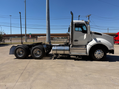 Kenworth T880 conventional daycab truck side view showing chrome fuel tanks and axle configuration with 3 rear axles and white cab