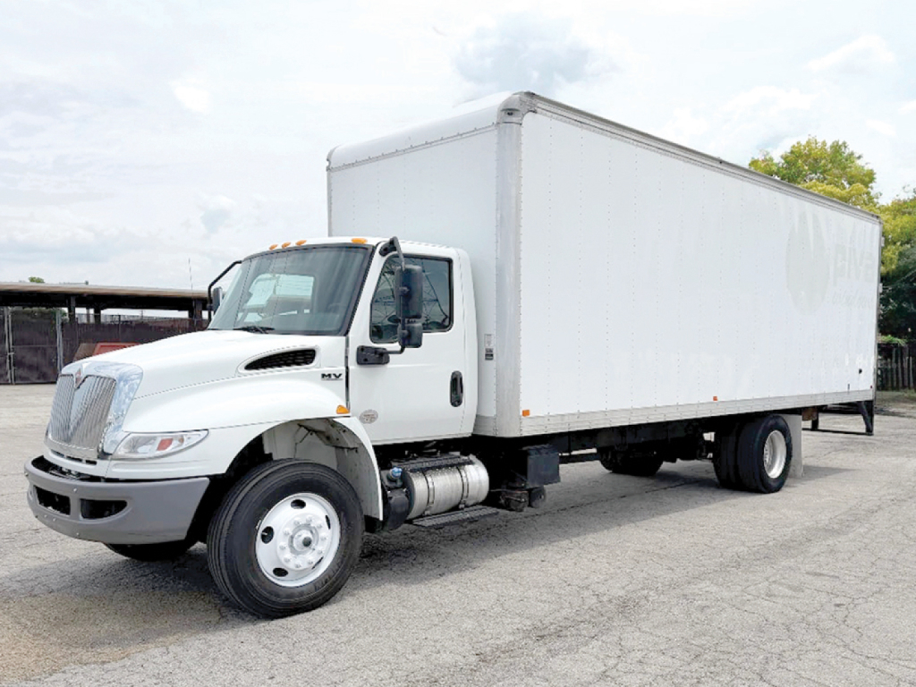International 4300 conventional daycab truck with a large white box trailer, side view showing cab and box, VIN 1HTEUTAN4PH495064, stock number 557472.