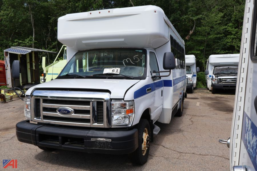 Ford E-350 wheelchair bus in-service showing front grille, headlights, and side blue stripe on white body.