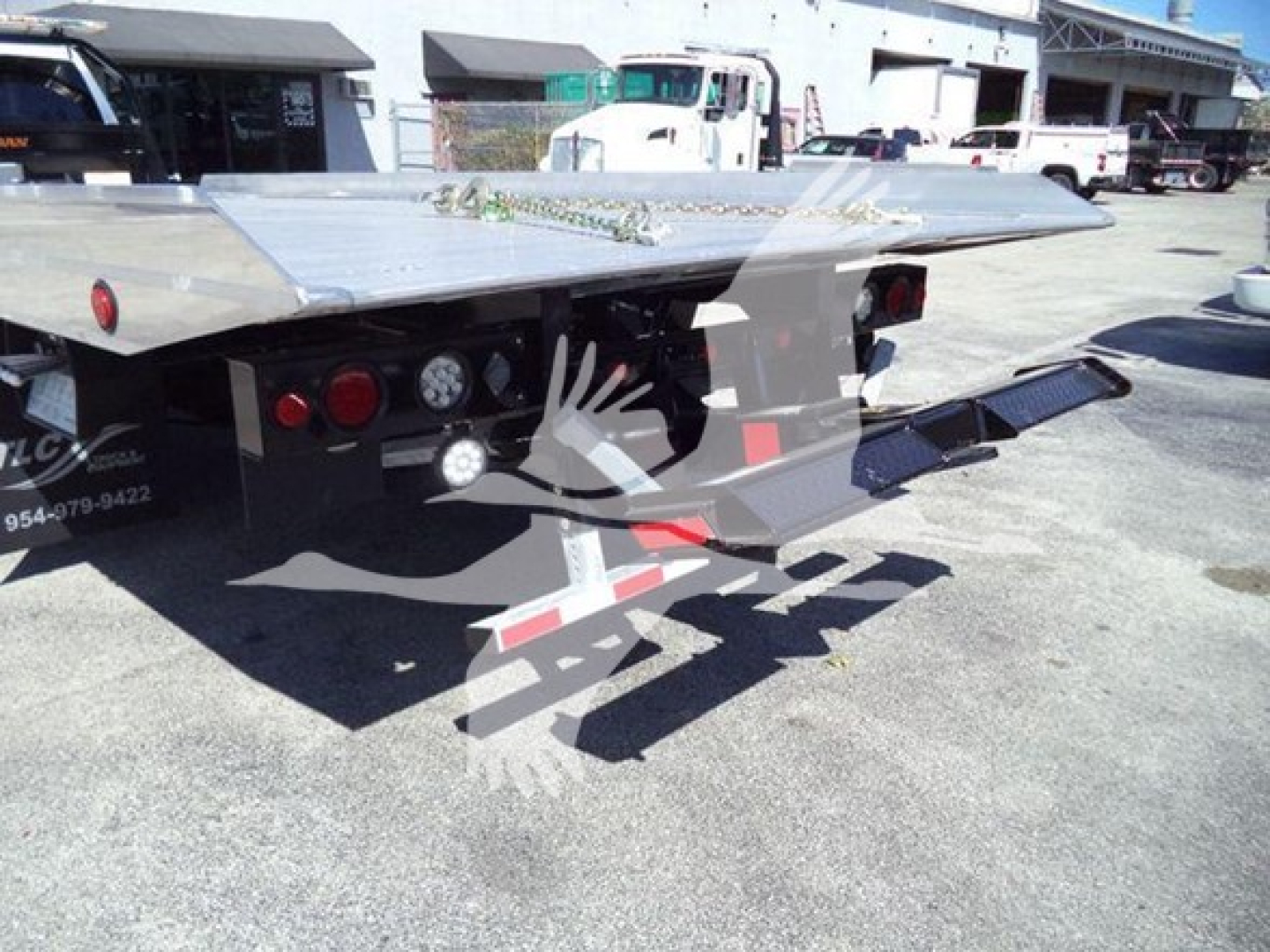 Flatbed tow truck platform with hydraulic ramps showing rear view and equipment on trailer, Ram 2026 Big Horn not visible in image